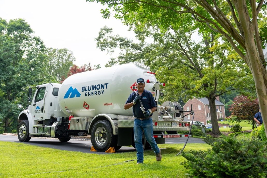 service technician pulling a hose from a propane truck in the background