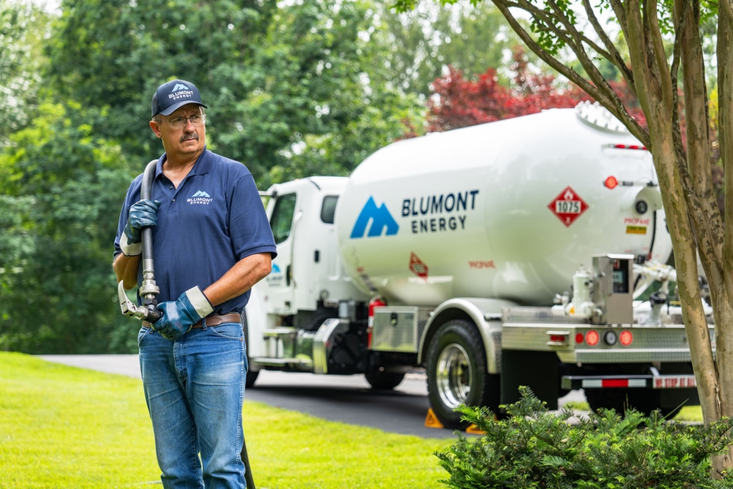 service technician pulling a hose from a propane truck in the background
