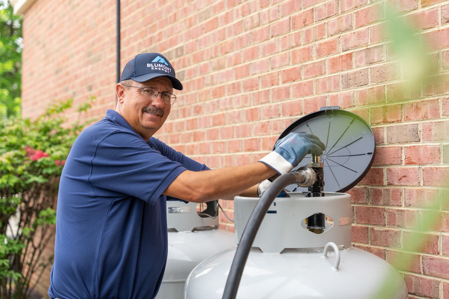 Happy Blumont Energy employee looking at the camera while filling a propane tank