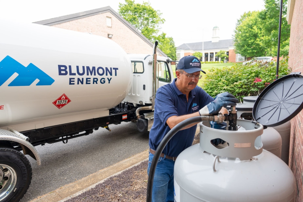Blumont Energy employee filling a propane tank with a propane truck in the background