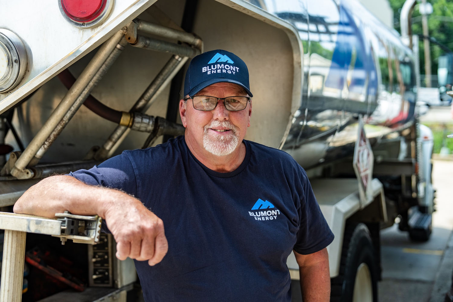 happy employee looking at the camera while leaning on a fuel truck