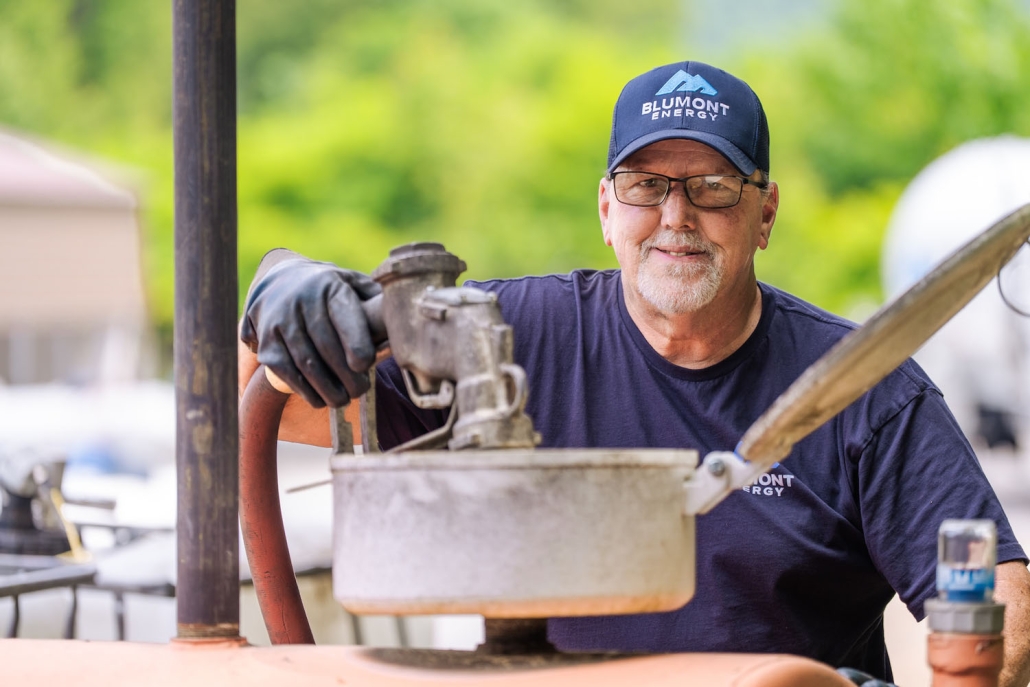 Happy Blumont Energy service technician looking at the camera while filling up a tank