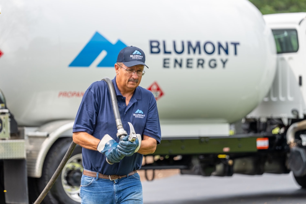 Blumont Energy service technician pulling a hose from a propane truck in the background