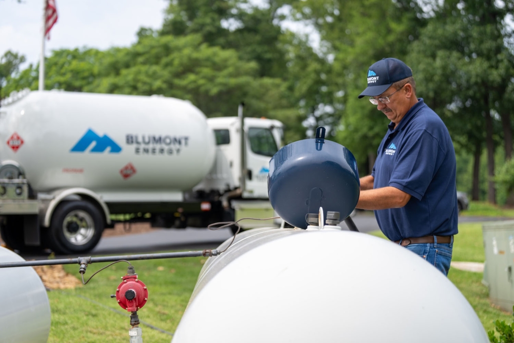 service technician filling a propane tank with a propane truck in the background